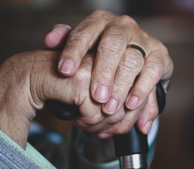 Caregiver's hands resting gently over an elderly resident's hands at a Seattle assisted living home